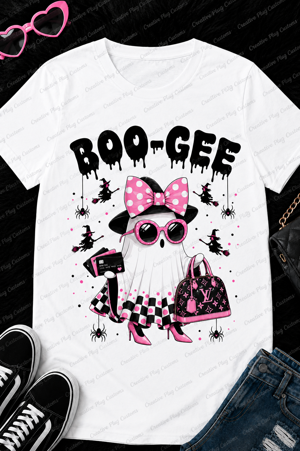 A white short-sleeve graphic T-shirt laid flat on a black textured background, styled with pink sunglasses, black sneakers, distressed blue jeans, and a black quilted handbag. The shirt features a Halloween-themed ghost graphic with the text 'BOO-GEE', a pink polka-dot bow, pink sunglasses, a black-and-white checkered dress, a pink-and-black Louis Vuitton-style handbag, and small black spider motifs.